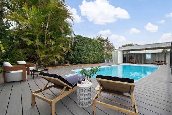 Two pool chairs on deck with balcony