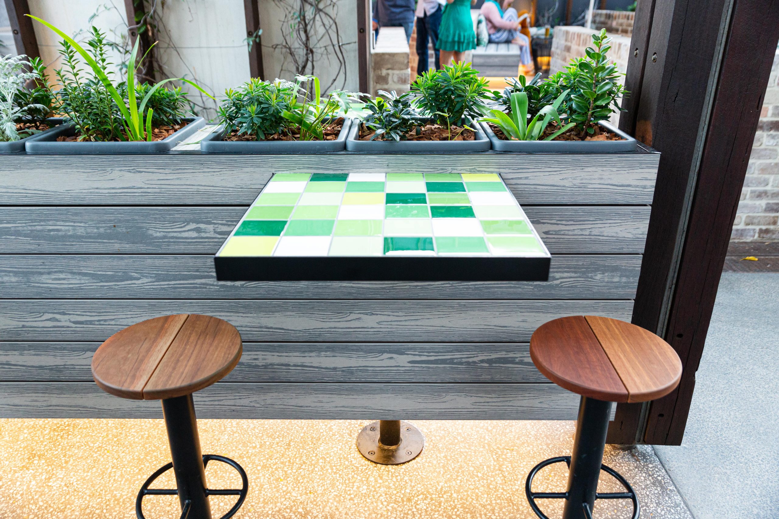 A tile checkered table installed into the side of a planter box wall