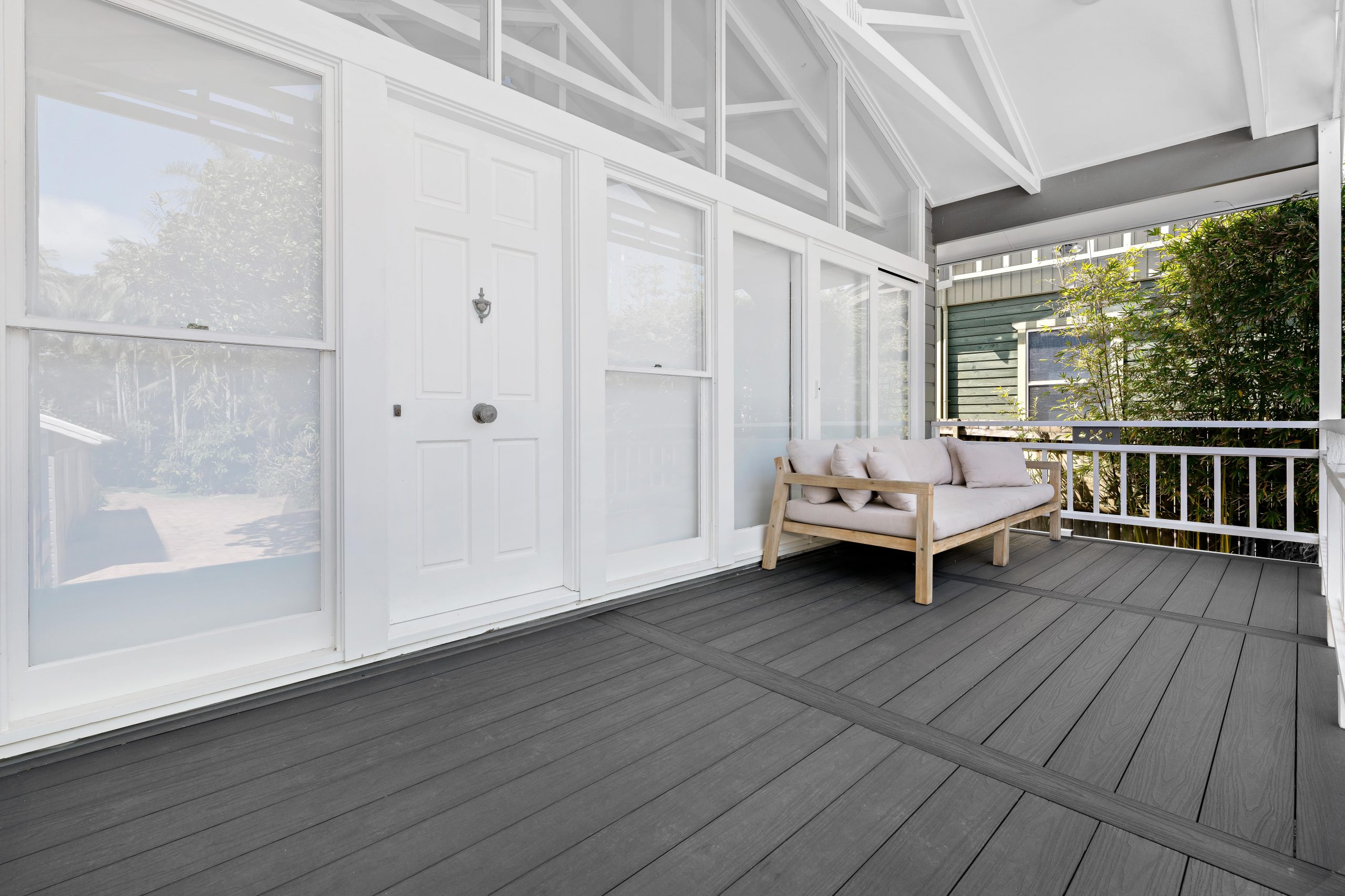 A large, gray composite deck patio leading to a home's front door