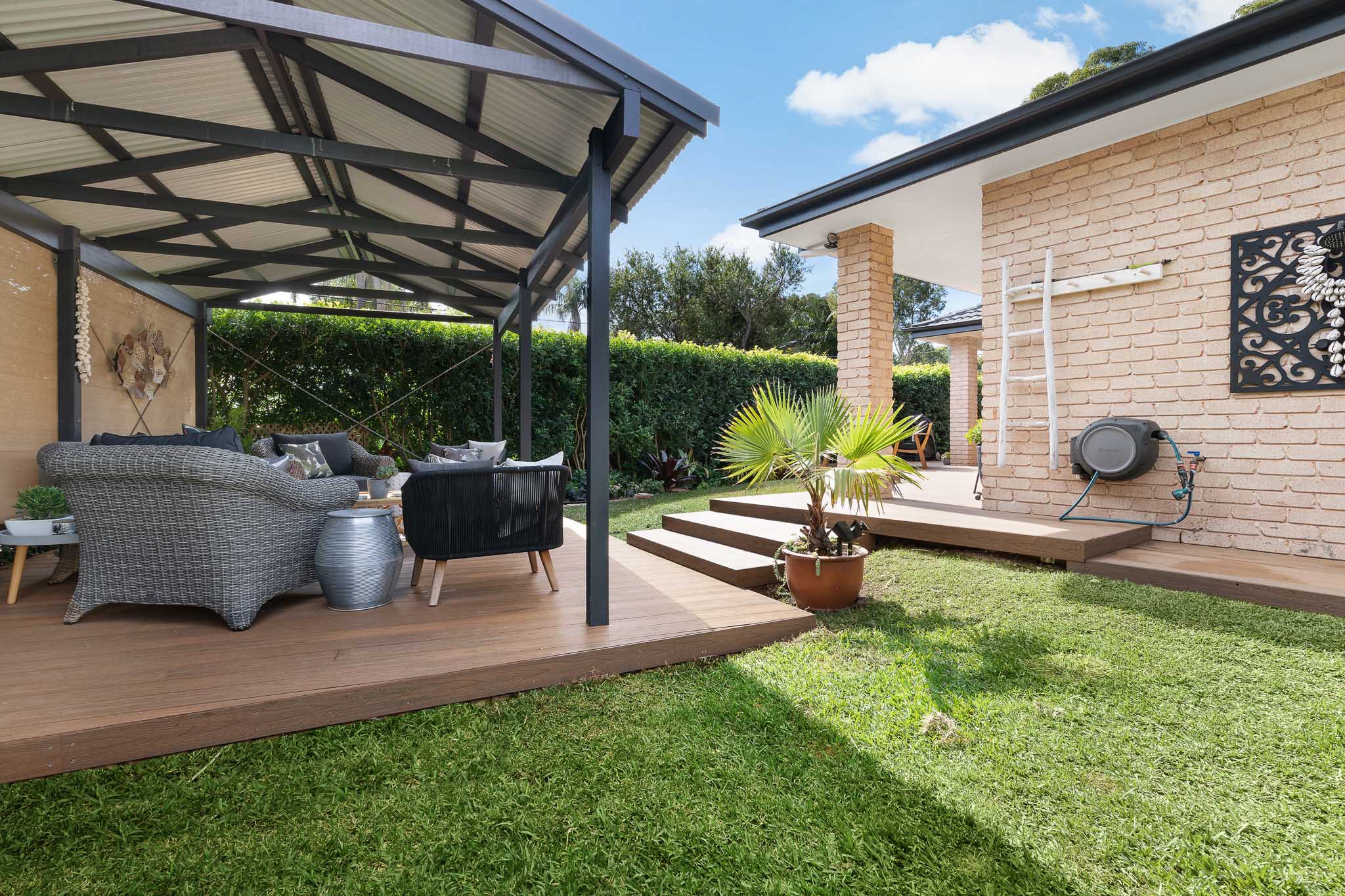Teak composite decking boards with patio furniture and a pergola above