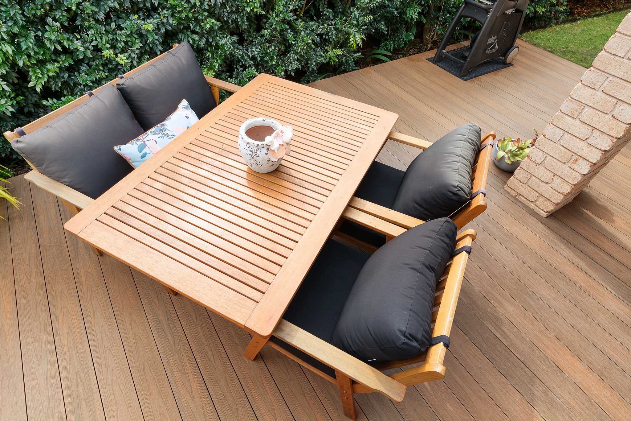 A close up of a wooden table and 4 patio chairs