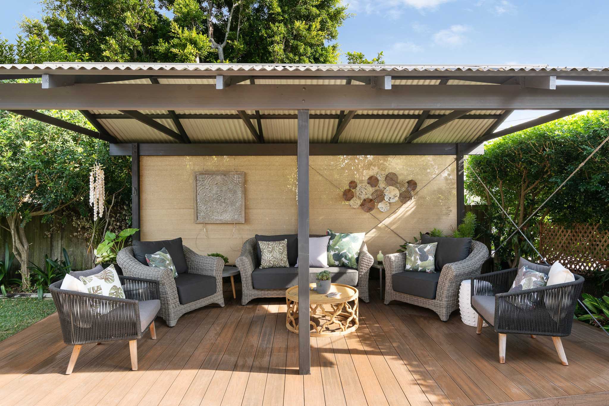 Dark gray patio furniture with a shady pergola above Teak composite decking boards