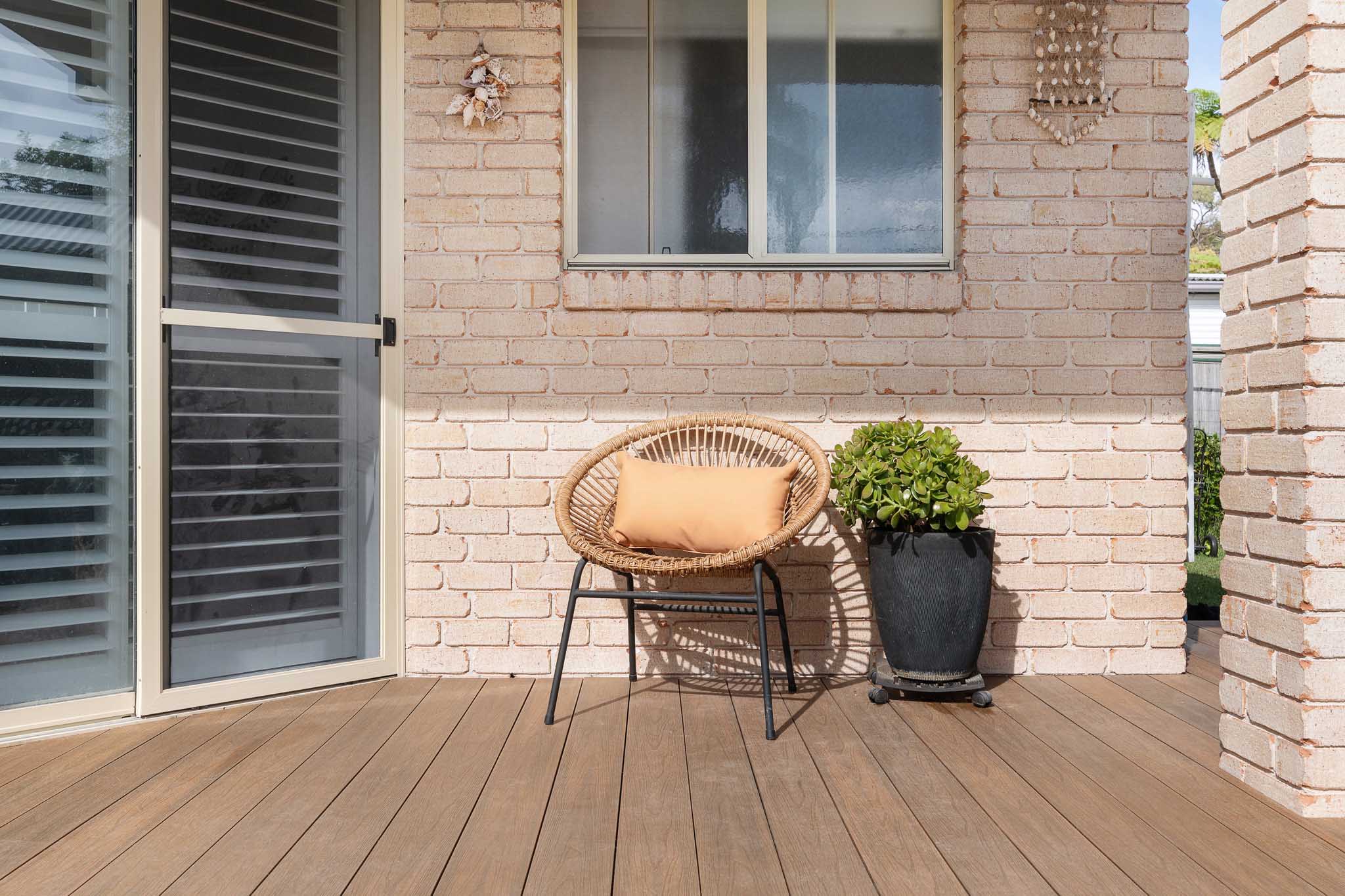 Teak composite decking boards with a cane chair on top