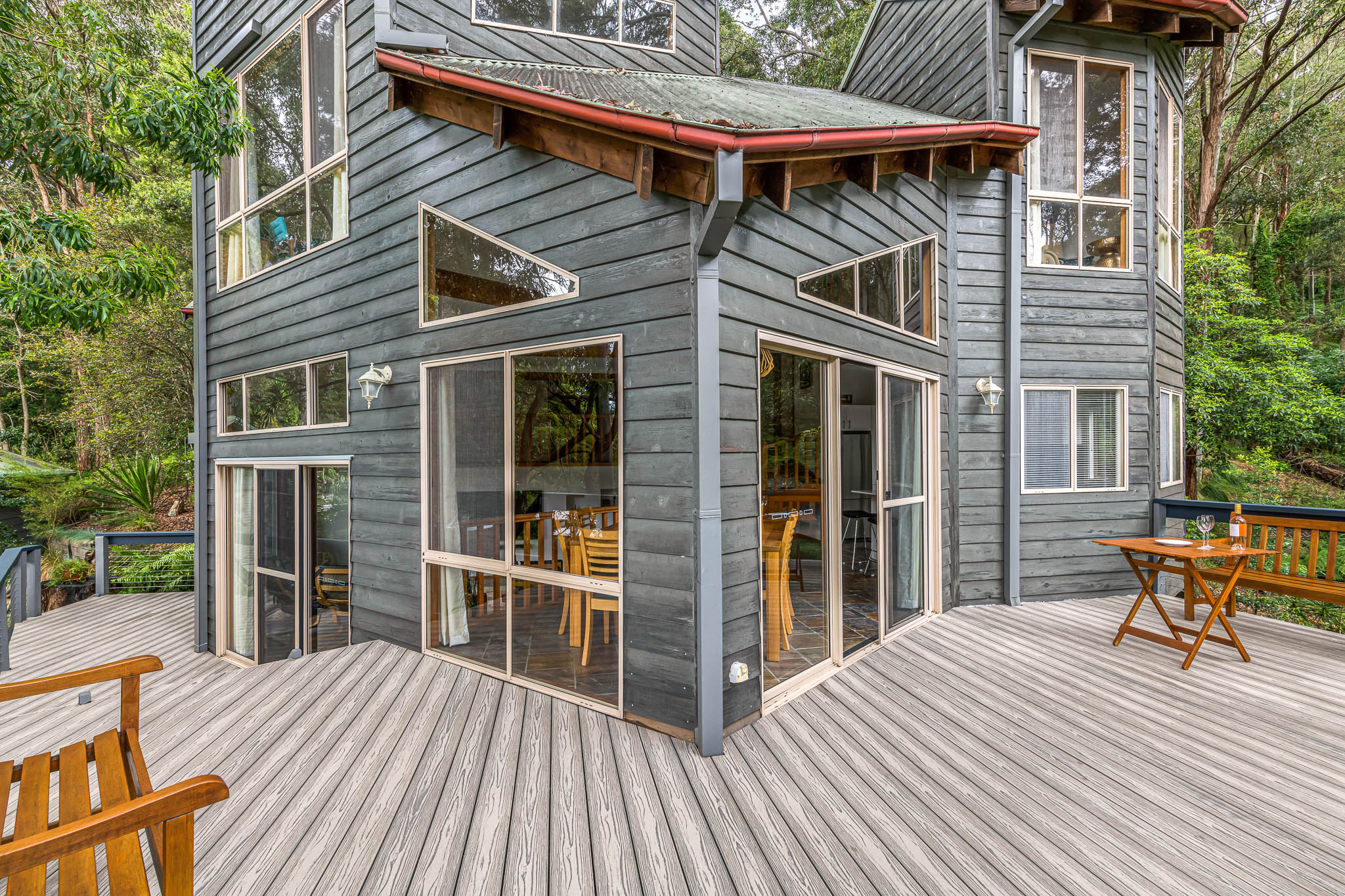 A blue rustic wooden home surrounded by gray-silver titanium decking boards