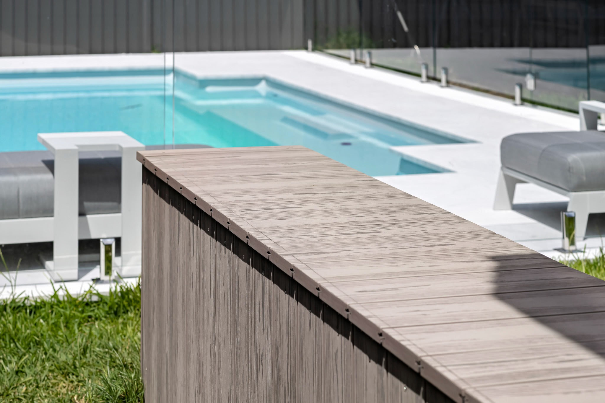 A ledge made from gray-silver composite deck boards overlooking a pool