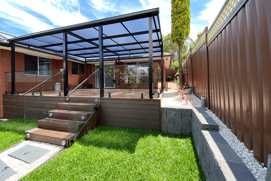 An elevated deck with composite decking boards and a glass pergola over top