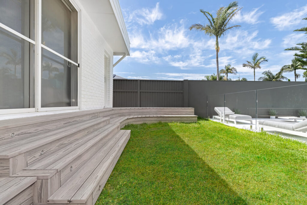a grey composite decking with steps and grass in front of a house