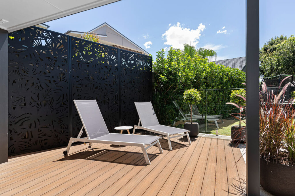 a composite decking installed on a patio with chairs and a fence