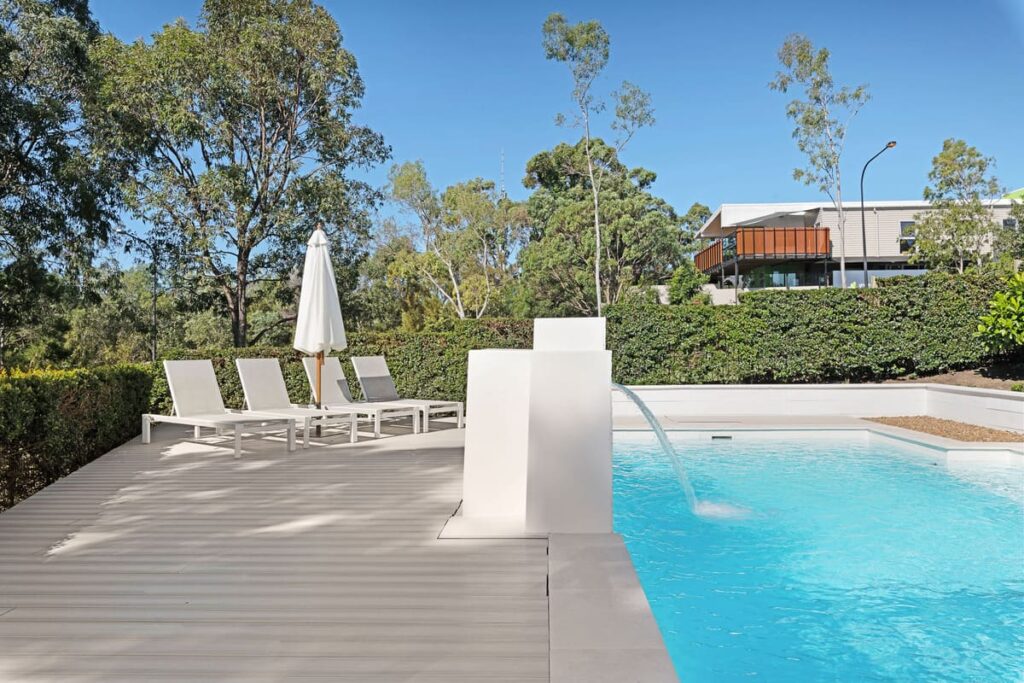 a poolside deck with a white umbrella and a white umbrella
