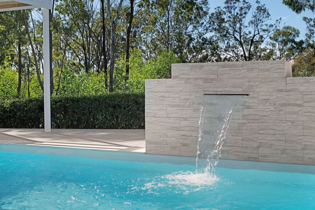 a composite deck installed beside the pool with a waterfall