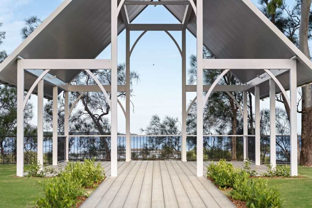 a white structure with a grey composite deck and trees