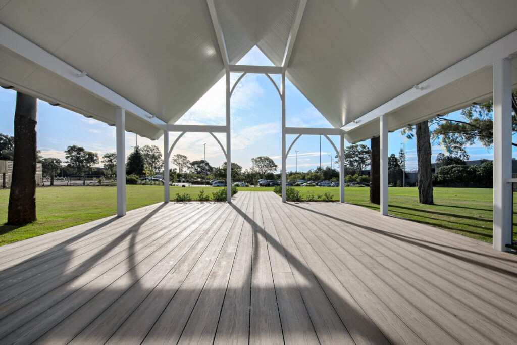 a grey composite deck with a large roof and grass and trees