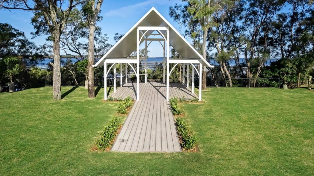 a white gazebo with grey composite decking installed on a grassy area