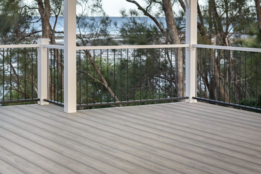 a grey composite deck with a railing and trees