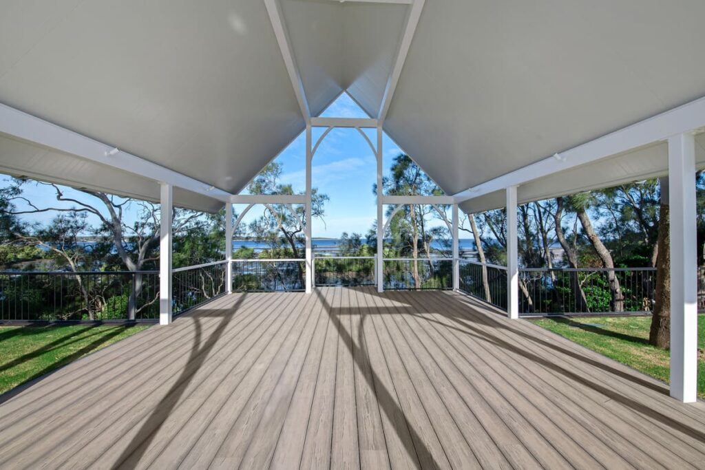 a grey composite deck with a roof and trees