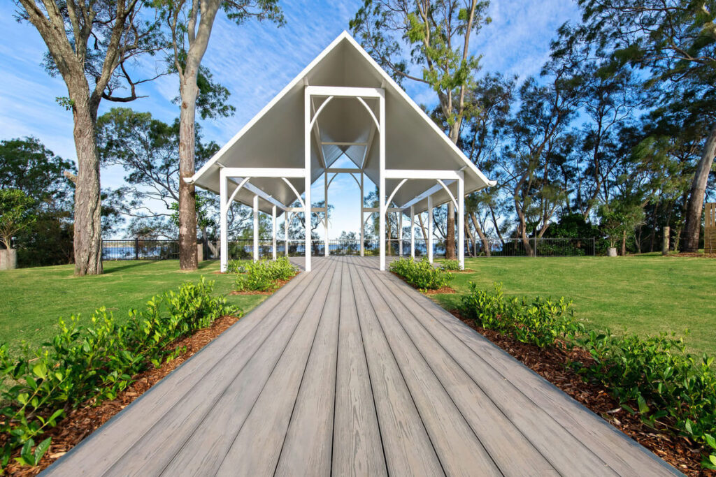 a grey composite decking walkway leading to a white structure
