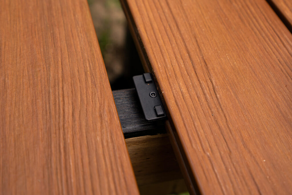Close-up of concealed fastener between Titanium Tawny composite decking boards during DIY installation for a tiny house deck in Byron Bay.