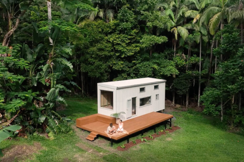 Aerial view of a tiny house with Titanium Tawny composite decking in Byron Bay, featuring built-in seating and surrounded by lush tropical forest.