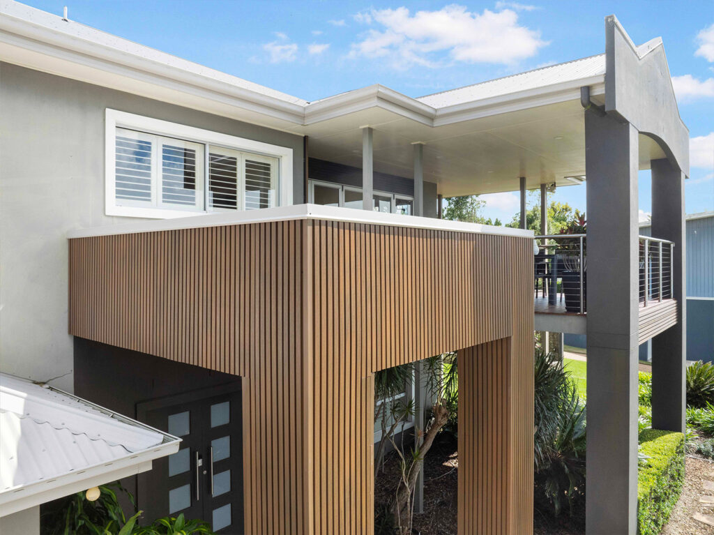 Angled close-up of entry clad in Country Teak composite cladding, highlighting vertical batten texture and sharp architectural lines.