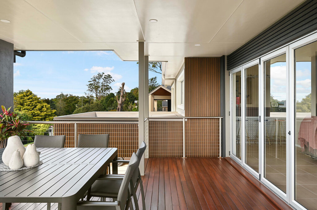 View from upper deck showing Country Teak composite cladding on balcony walls, with timber flooring, railing, and sliding glass doors.