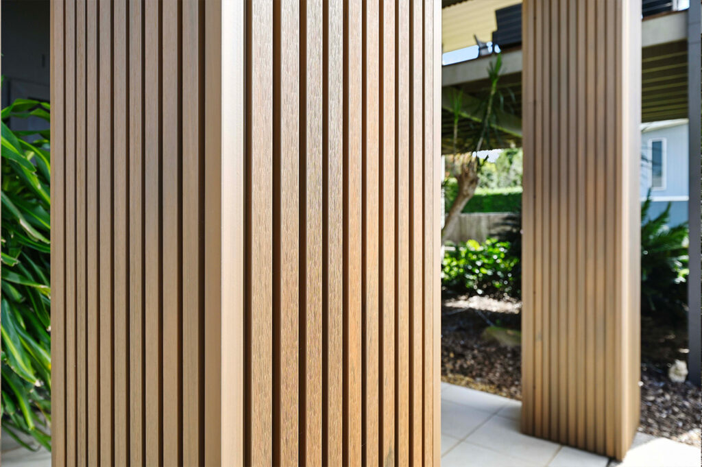 Macro detail of Country Teak composite cladding batten profile, highlighting its rich texture and vertical alignment on structural columns.