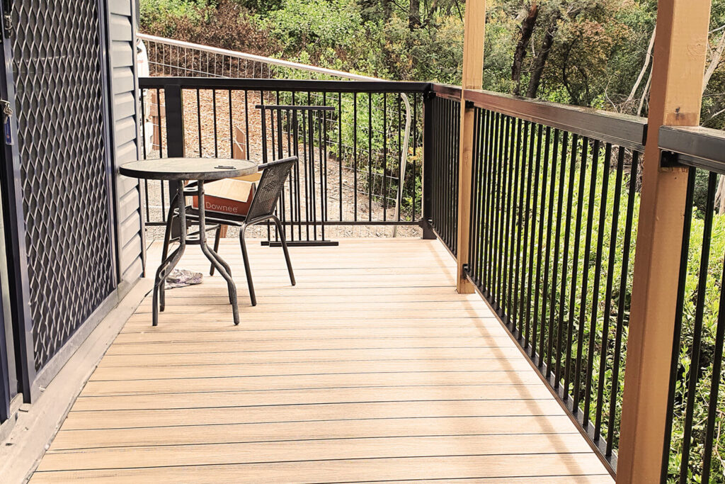 Outdoor cabin balcony with table, chairs, and composite decking Tasmania in Hobart holiday park.