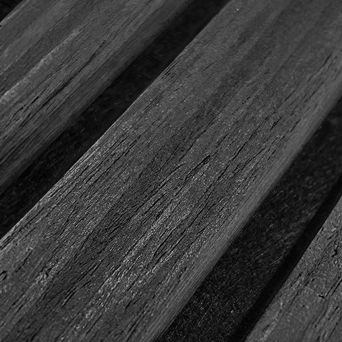 MDF acoustic panel texture in Raven Black, close-up showing woodgrain slats and shadowed grooves.