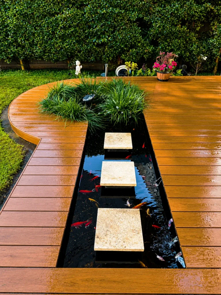 Composite decking Homebush showcasing HD PRO Aussie Redwood with stepping stones across a decorative pond and custom curved decking.